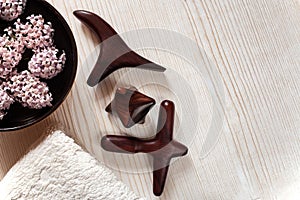 SPA and massage concept. Wooden massage sticks, terry towel, bowl with flowers on wooden background.