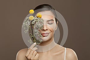 Spa model woman with perfect clear skin and flowers on brown background. Eyes closed. Herbal medicine and skincare concept