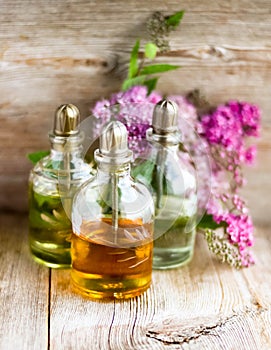 Spa perfume essential aroma oil glass bottles with flower blossoms on old wooden background