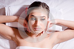 Spa portrait of young beautiful woman with orchid lying on her back and relaxing with bare shoulders looking dreamy