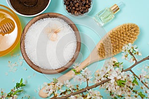 Spa products for home body care for cellulite and acne. sea salt, coffee scrub, honey in plates on a blue background and a flower