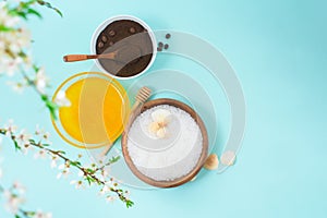 Spa products for home body care for cellulite and acne. sea salt, coffee scrub, honey in plates on a blue background and a flower