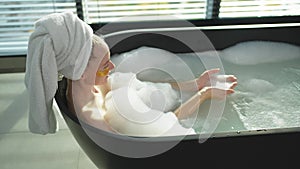Spa relaxation. Young woman lying in bath with foam bubbles. Girl relaxing in bathroom at home. Pretty female spending