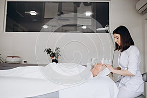 spa, resort, beauty and health concept - beautiful woman in spa salon getting face treatment.