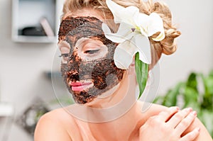 Spa salon. Beautiful woman with chocolate facial mask at beauty salon