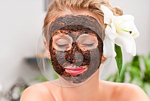 Spa salon. Beautiful woman with facial mask at beauty salon