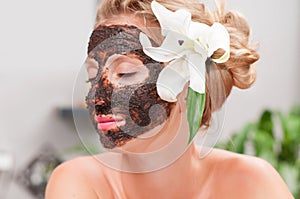 Spa salon. Beautiful woman with facial mask at beauty salon