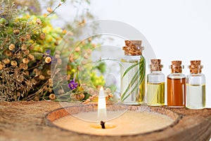 Spa set with burning candle, essential oils in bottles, herbs and flower