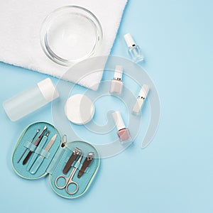 Spa set, manicure or pedicure equipment with nail coat or polish, on blue background, top view, copy space, square