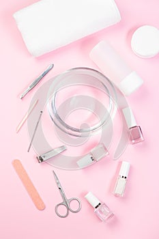 Spa set, manicure or pedicure equipment with nail coat or polish, on pink background, vertical, top view