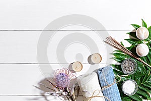 Spa set with sea salt, essential oil, soap and towel decorated with dry flower on white wooden background