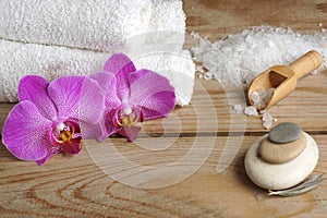 Spa set with white salt for bath, flowers of orchid and towels on a wooden background