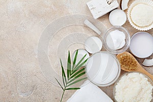 Spa setting from body care, wellness and beauty treatment. Organic coconut scrub, oil and cream on stone table top view. Flat lay.