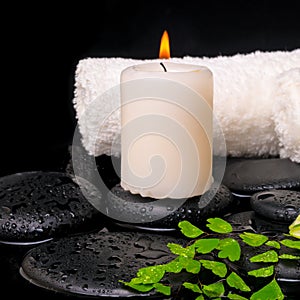 Spa setting of green branch fern, towels and candle on zen stone