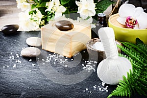 Spa setting with herbal massage ball, flowers and essential oil