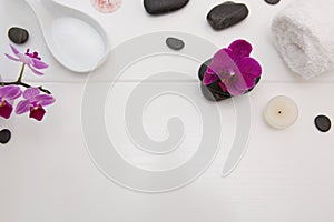 Spa setting with pink orchids, black stones on white wood background.