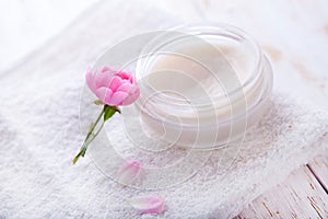 Spa setting with pot of moisturizing cream beautiful pink roses and rose oil on white background top view
