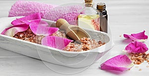 Spa setting with rose bath salt, rose petals and body-care oil b