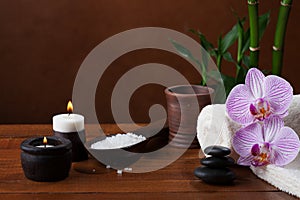 Spa setting with sea salt, candles, towels, stones and orchids