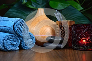 Spa still life with electric aromatherapy diffuser, massage stones, towels and candle on wooden background stock photo images