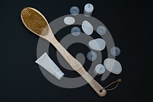 Spa still life with scented candles, treatment stones, cream and massage brush against a dark background. Flyer