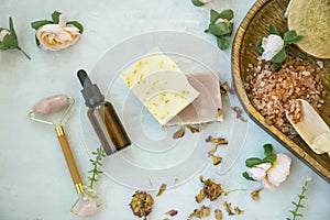 Spa still life setting with natural soap, rose quartz face roller, rose oil bottle and bath salt