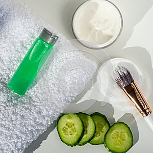 Spa still life with towels. The concept of home skin care. A green cucumber for making a cosmetic mask and a brush with a towel on