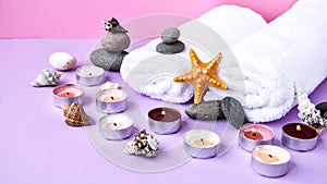 Spa still life treatment with candles, stones, sea shells starfish and towels on pink background