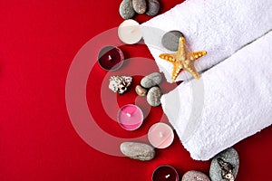 Spa still life treatment with candles, stones, sea shells starfish and towels on red background