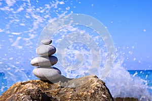 Spa stones balance on beach and sea waves crashing .