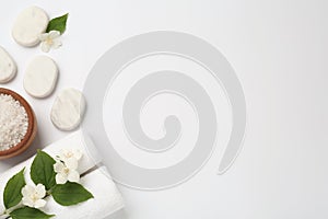 Spa stones, beautiful jasmine flowers, sea salt and towels on white background, flat lay. Space for text