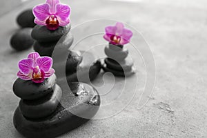 Spa stones and beautiful orchid flowers on grey table