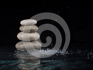 Spa Stones. black shiny zen stones with water drops over black background. Zen stones pile in raindrops, concept of calm, peace