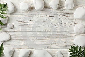 Spa stones and fern branches on white wooden background