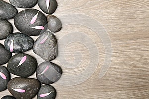 Spa stones with flower petals on wooden background, flat lay