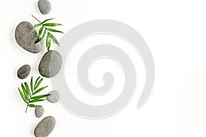 Spa stones, palm leaves, candle and zen like grey stones on white background. Flat lay, top view