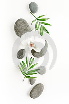 Spa stones, palm leaves, candle and zen like grey stones on white background. Flat lay, top view