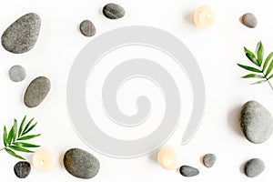 Spa stones, palm leaves, flower white orchid, candle and zen like grey stones on white background. Flat lay, top view