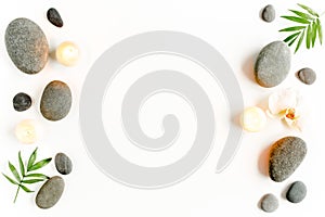 Spa stones, palm leaves, flower white orchid, candle and zen like grey stones on white background. Flat lay, top view