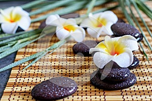 Spa straw napkin background, white plumeria, bamboo and zen stones balance. Spa aromatherapy, relaxation concept