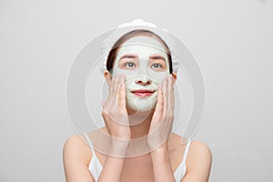 Spa teen Asian girl applying facial clay mask. Beauty treatments. Over white background