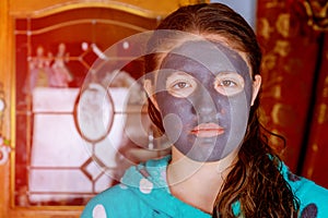 Spa teen girl applying facial clay mask. Beauty treatments. Over blue background.