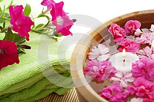 Spa therapy, flowers in water, on a bamboo mat.