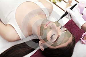 Spa therapy for young woman having facial mask at beauty salon