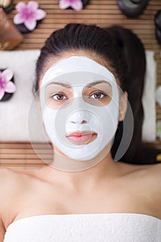 Spa therapy for young woman having facial mask at beauty salon