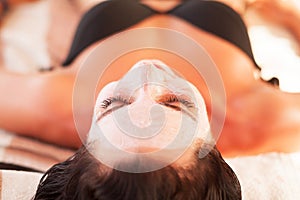 Spa therapy for young woman having facial mask at beauty salon -