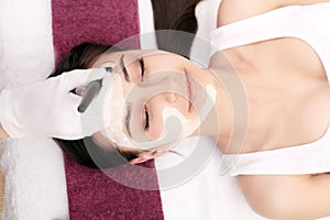 Spa therapy for young woman having facial mask at beauty salon -