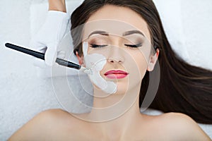 Spa therapy for young woman having facial mask at beauty salon -