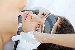 Spa therapy for young woman having facial mask at beauty salon -