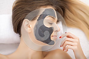 Spa therapy for young woman having facial mask at beauty salon -